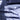 Close-up of draped bedding in a muted blue-gray color, with soft folds and shadows from natural light. #color_denim